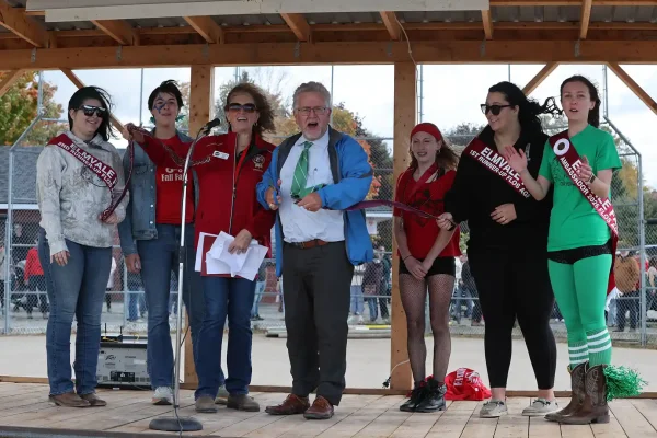 Senator Rob Black cuts the ribbon at the Elmvale Fall Fair Opening Ceremonies, joined by fair directors and Fair Ambassadors on a windy day at the Ball Diamond.