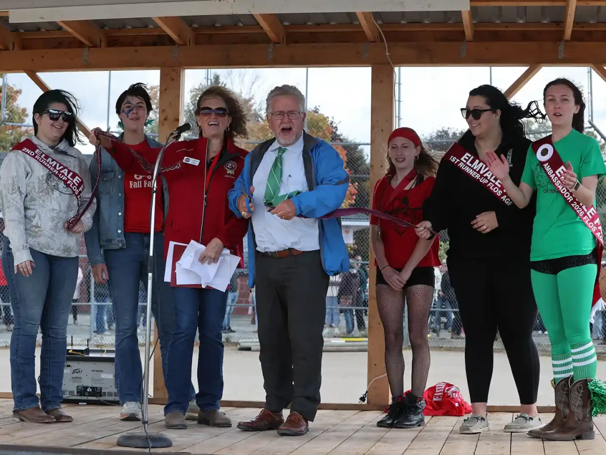 Senator Rob Black cuts the ribbon at the Elmvale Fall Fair Opening Ceremonies, joined by fair directors and Fair Ambassadors on a windy day at the Ball Diamond.